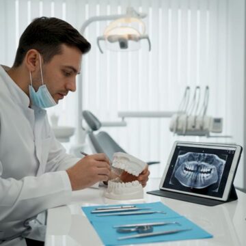 Medic stomatolog explicând pacientului structura osoasă cu ajutorul unui model